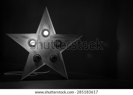 Single red soviet star lamp display with broken bulbs in black and white