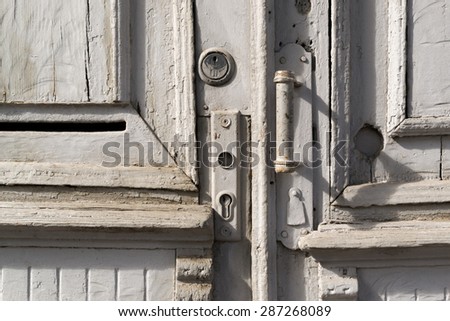 Grey worn painted wooden door with metal handle and lock