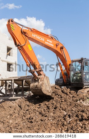 UFA/BASHKORTOSTAN - RUSSIA 13th June 2015 - Orange digger excavates soil in preparation for new apartments for young families in Ufa city Bashkortostan Russia in June 2015