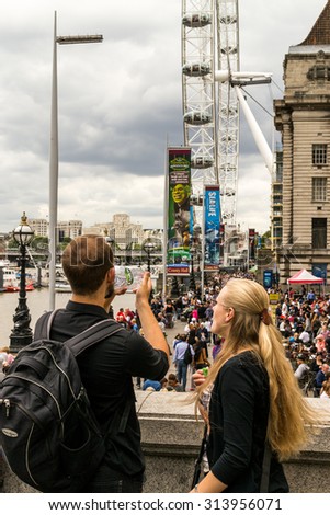 LONDON - ENGLAND 18TH AUGUST 2015 - Young tourists drink water outside the London Eye tourist attraction in the summer of August 2015
