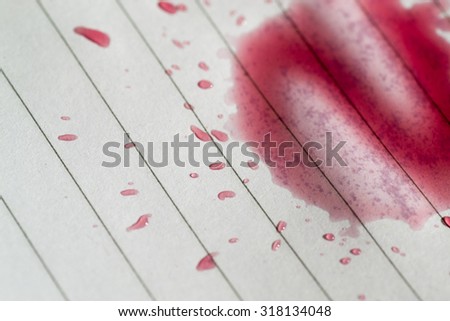 Closeup Macro image of a red wine stain on a pad of clean lined paper