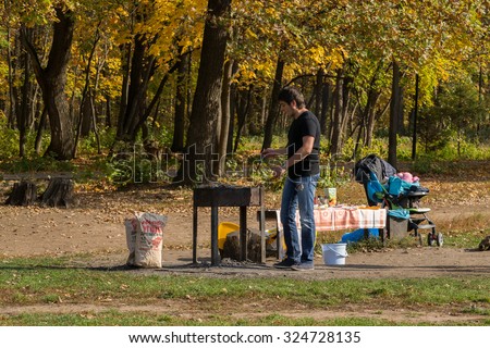 UFA - RUSSIA 25TH SEPTEMBER 2015 - Young man prepares a Shashlik BBQ grill to cook fresh meat in a park in Ufa, Russia during the Autumn of 2015