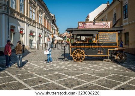 Brasov, Romania - September 25, 2015: Tourists and locals walking in historical center of Brasov near the retro style kiosk. Brasov is a popular tourism destination