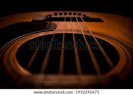 Guitar.Guitar's chords.Acoustic guitar.Music.Music background.Image of an acoustic guitar in the dark.Playing music with some friends in the dark.Classical music.Closeup image of an acoustic guitar.