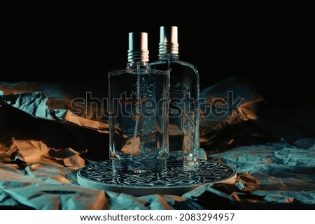 Perfume, two men's perfume bottles standing on a paper background, a perfume bottle with a men's label, a background with a hard shadow and crumpled paper pattern, teal and yellow light contrast