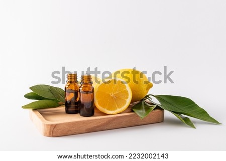 two medical bottles with a dropper with essential lemon oil stand on a wooden tray among ripe lemons. aromatherapy. massage. antioxidant. vitamin C Stok fotoğraf © 