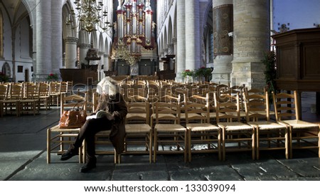 HAARLEM, NETHERLANDS -DEC 1: The church,Grote Kerk, is almost empty except one woman reading bible on December 1, 2012 in Haarlem, Netherlands. The number of christian church members has been falling.