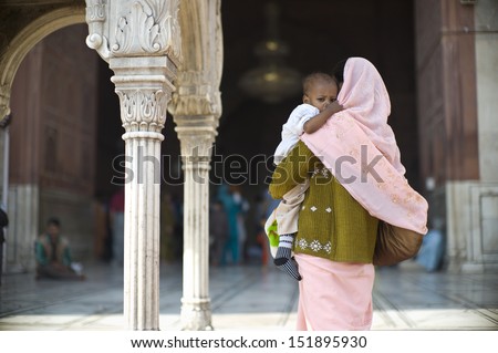 DELHI, INDIA - NOV 16: An unidentified woman and baby rest on the courtyard of Jama Masjid Mosque on October 16, 2012 in Delhi, India. Jama Masjid is the principal mosque of Old Delhi in India.