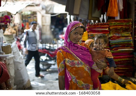 JODHPUR, INDIA - FEB 1: An unidentified woman and her kid in colorful attire is shopping in the market on February 1, 2013 in Jodhpur, India. The clothes of Rajasthan woman are famous for the color.
