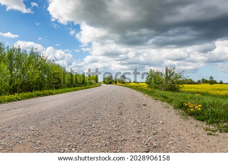 Image, Stock Photo Country road and path surrounded by fields with barley and rape, two trees standing at the roadside in front of a blue sky with little clouds and sunshine