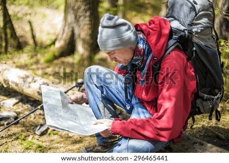 young caucasian male with a map in the forest, hiker looking at map outdoors