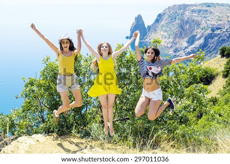 three young cheering friends jumping on a cliff above the sea