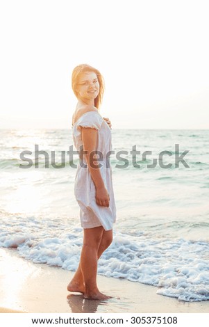 young beautiful caucasian female enjoying the sun on beach during sunrise or sunset
