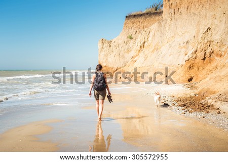young caucasian female with backpack and  siberian husky dog on beach, hiker woman with dog on seaside