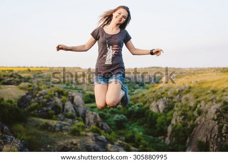 young caucasian female jumping in canyon, girl having fun on beautiful natural landscape with rocks