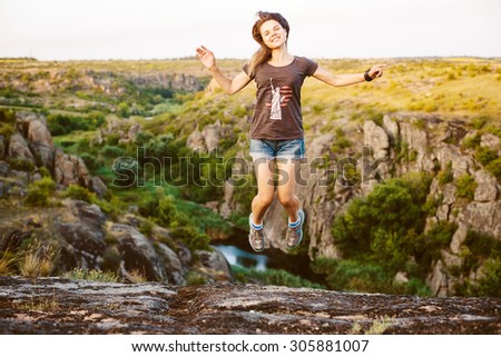 young caucasian female jumping in canyon, girl having fun on beautiful natural landscape with rocks