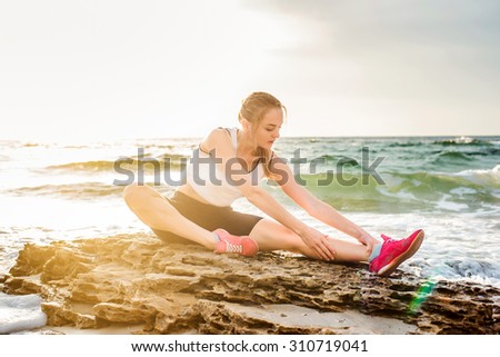 Fitness sport model  doing exercises during outdoor work out on sunrise. Beautiful caucasian female training outside on seaside in the morning
