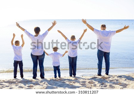 happy family of mother, father and three sons cheering on beach. Family enjoying the sunrise sunlight on seaside during summer vacations, family on vacations concept