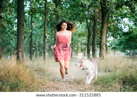 young beautiful caucasian female training with siberian husky puppy in park