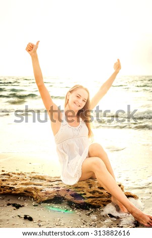 young beautiful caucasian female enjoying the sun on beach during sunrise or sunset