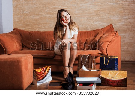 young caucasian female with shopping bags talking on mobile phone in living room.