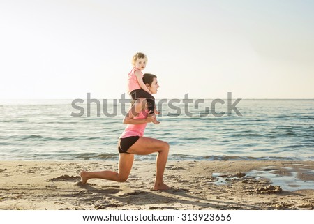 family workout - mother and daughter doing exercises on beach. Mom and child working out on seaside in the morning. Healthy lifestyle concept