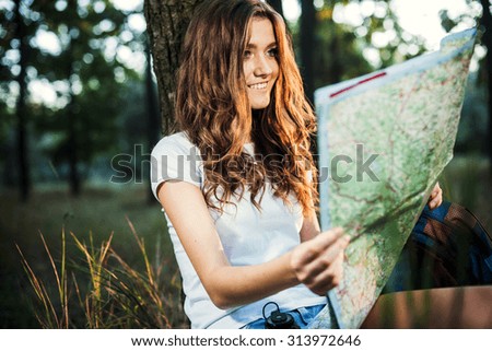 young caucasian female with backpacks and map in wood, hiker looking at map and try to find a way