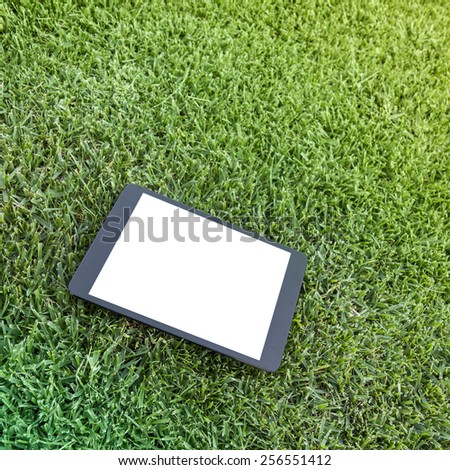 Tablet with a blank display on a green meadow. Copy space image.