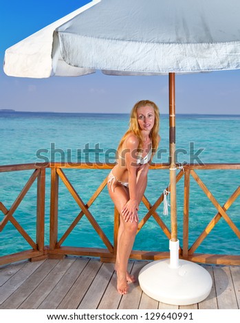 Young woman tans on a water villa terrace , Maldives