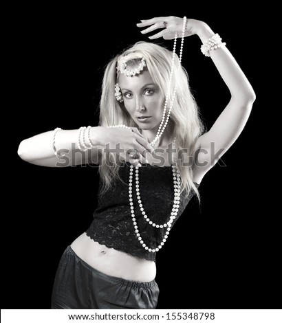 beautiful young blonde woman with long hair and a pearl dances an oriental dance on dark background