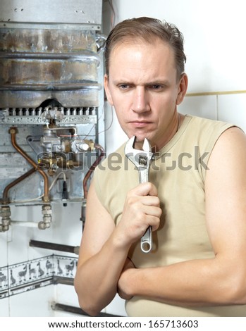 The man with a wrench thinks of repair of a gas water heater
