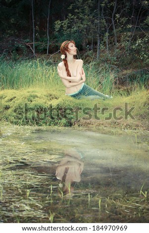 The girl sits on the bank of wood lake,with a retro effect