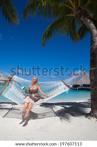the beautiful woman in a long sundress in a hammock on a sea background
