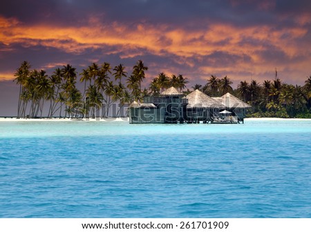 Island in ocean, overwater villas at the time sunset
