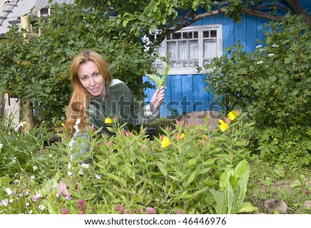 Young pretty woman looks after behind plants in the garden