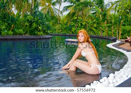 Young pretty woman in pool in tropical garden