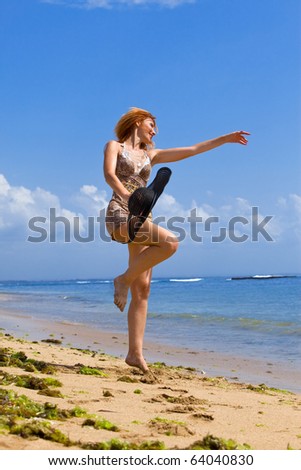 Young graceful woman goes on coast of ocean with straw hat in hands