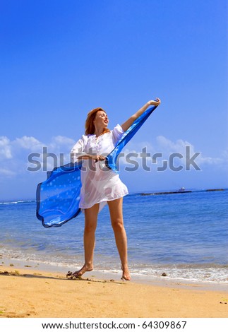 Young graceful woman  in white tunic with cape in hands on coast of ocean