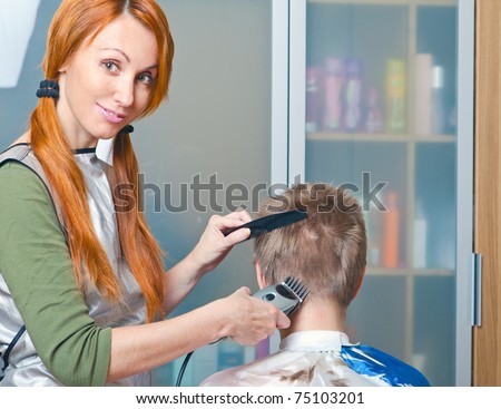 The beautiful young woman the hairdresser does a  hairstyle to the client - young man