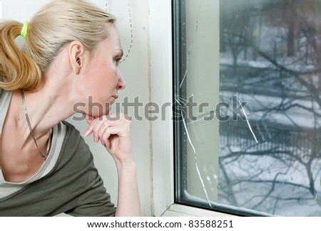 The housewife is upset, because the double-glazed window of bad quality has burst because of a frost