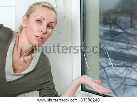 The housewife is upset, because the double-glazed window of bad quality has burst because of a frost