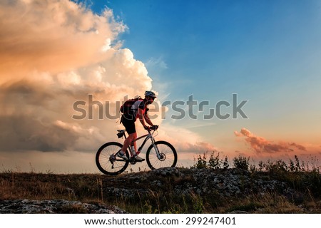 Biker riding on bicycle in mountains on sunset