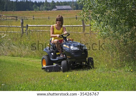 The young woman on riding lawn mower