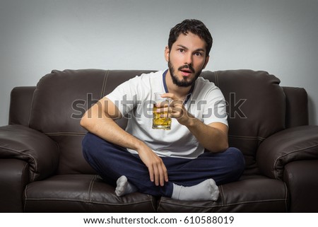 Young man watching sports match on tv at home. Very focused on it, holding a beer mug. Photo stock © 