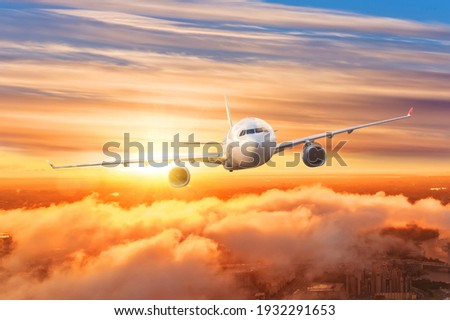 Airplane above the clouds in the sky at sunrise