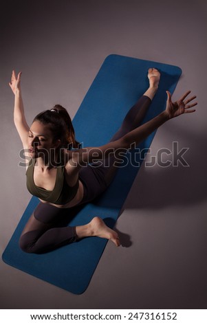 Mature woman practicing yoga in pigeon pose with outstretched arms