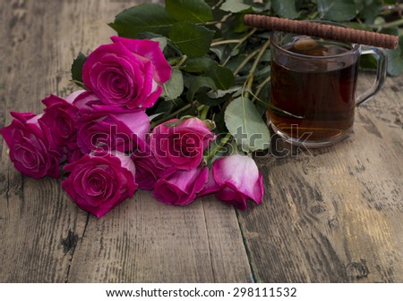 glass of strong tea, cookies and bouquet of scarlet roses