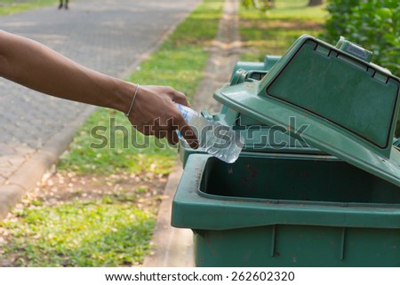 Hand throwing bottle in trash cans.