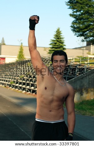 A male athlete smiling while holding his fist in the air