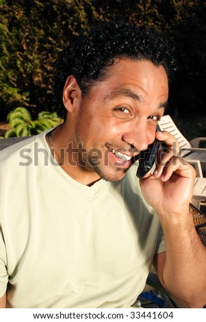 A man smiling at the camera and talking on his cell phone